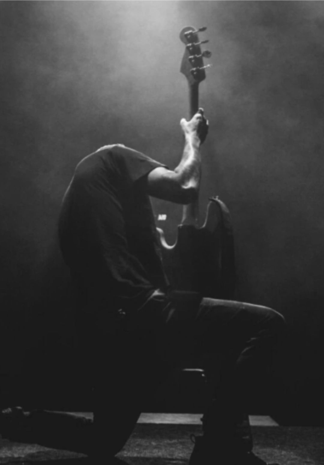 Guitarist kneeling down while playing at a concert 